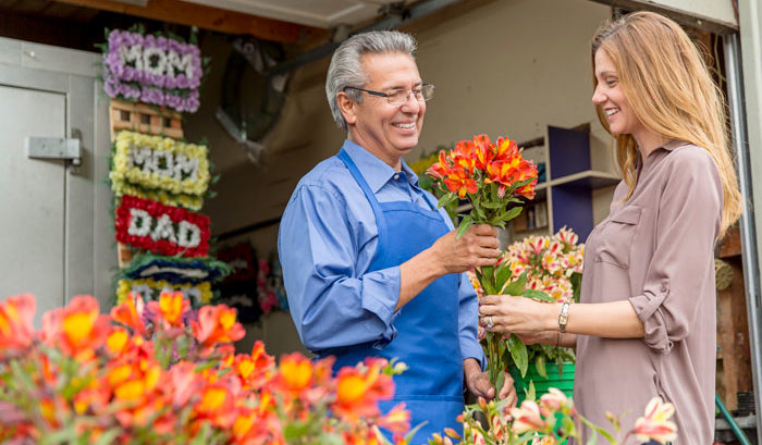 elderly male florist present young woman customer with flowers