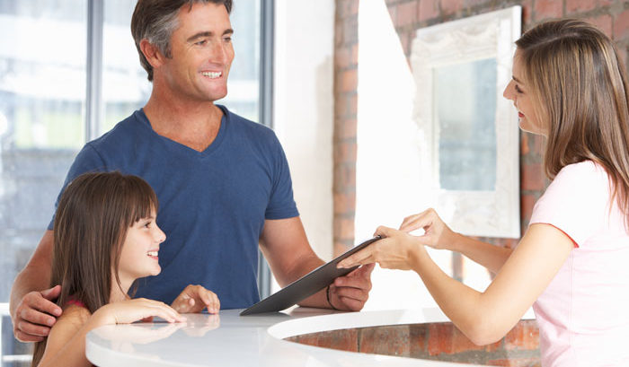 man with daughter at an office receiving paperwork and smiling