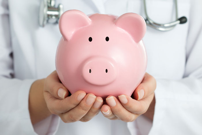 medical professional holding a pink piggy bank