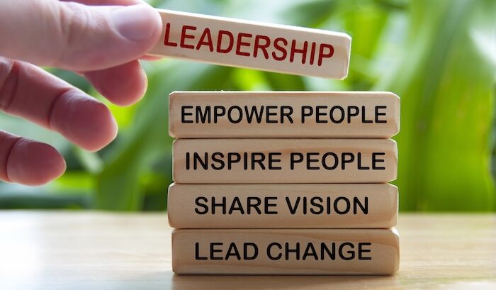 Hand holding wooden blocks with text - Leadership, empower people, inspire people, share vision, lead change.